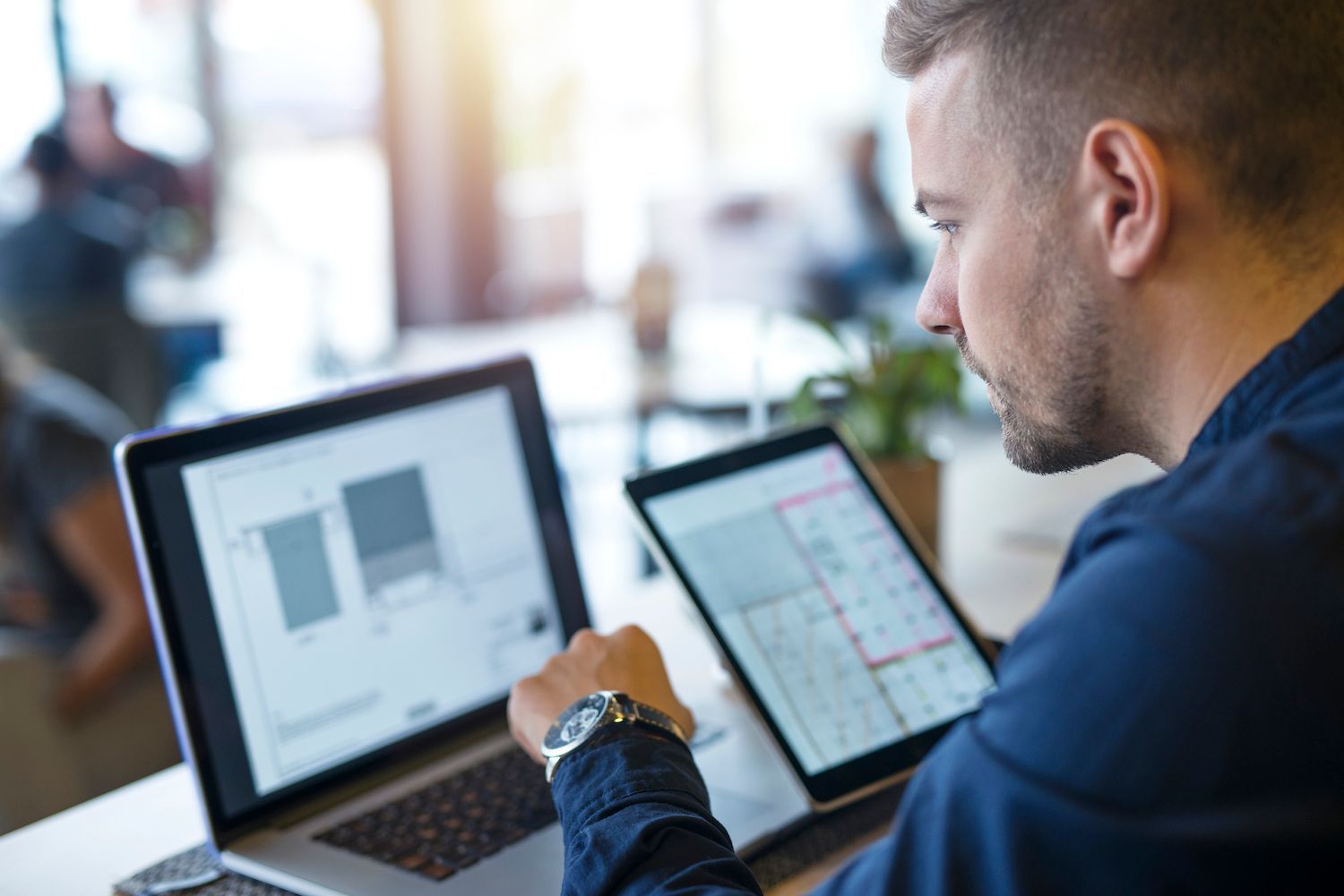 man discussing something with a colleague in front of a laptop